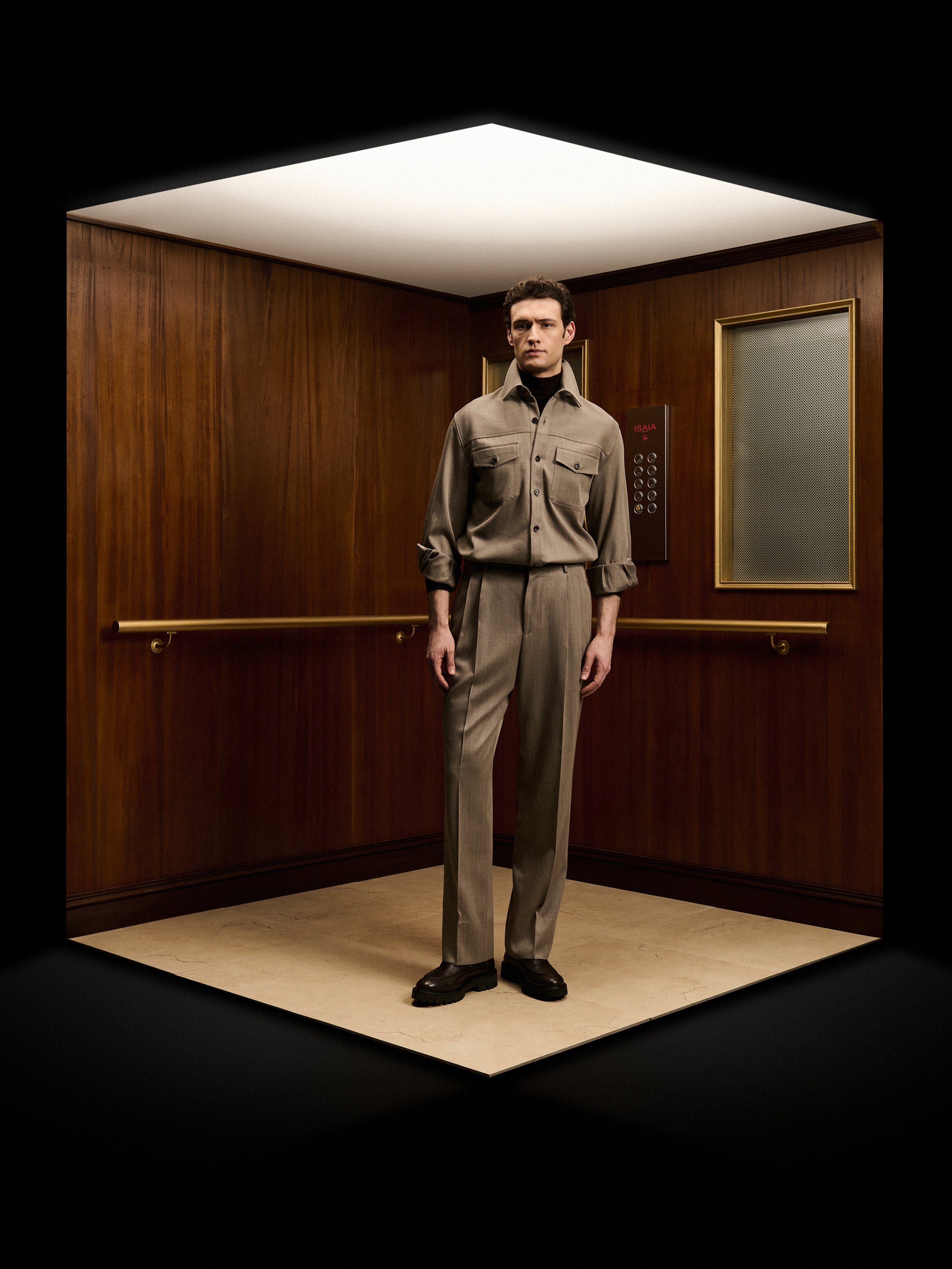 ISAIA Fall Winter 2026 collection featuring a man wearing a luxury sand-colored tailored suit in an elevator, showcasing Italian tailoring, contemporary elegance, and premium menswear craftsmanship.